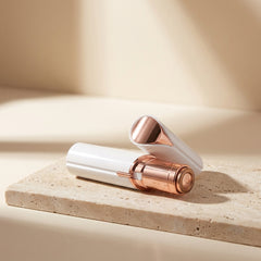 The Milara Face Shaver uncapped on travertine stone showing its gold foil head